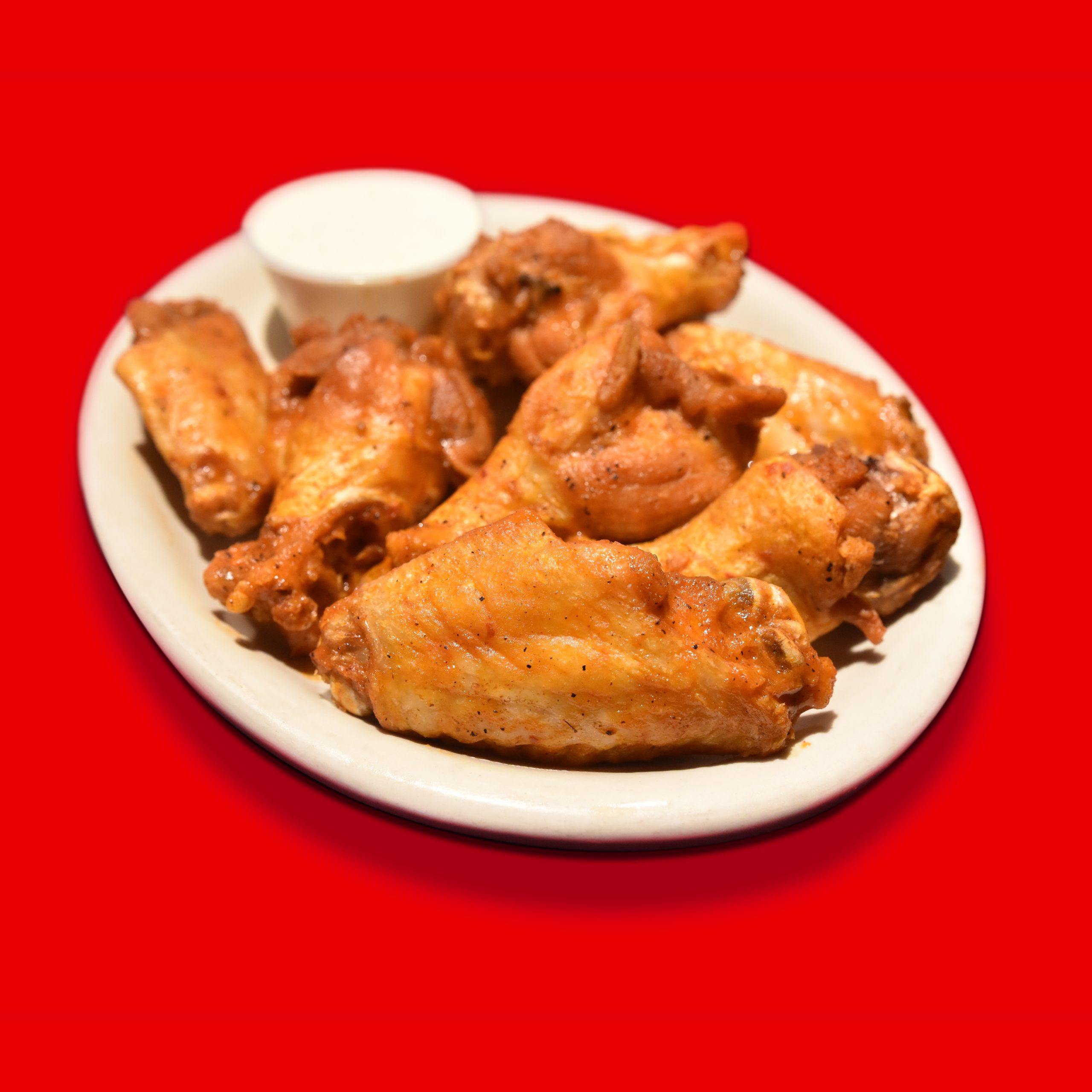 Plate of trashed boneless wings over red background
