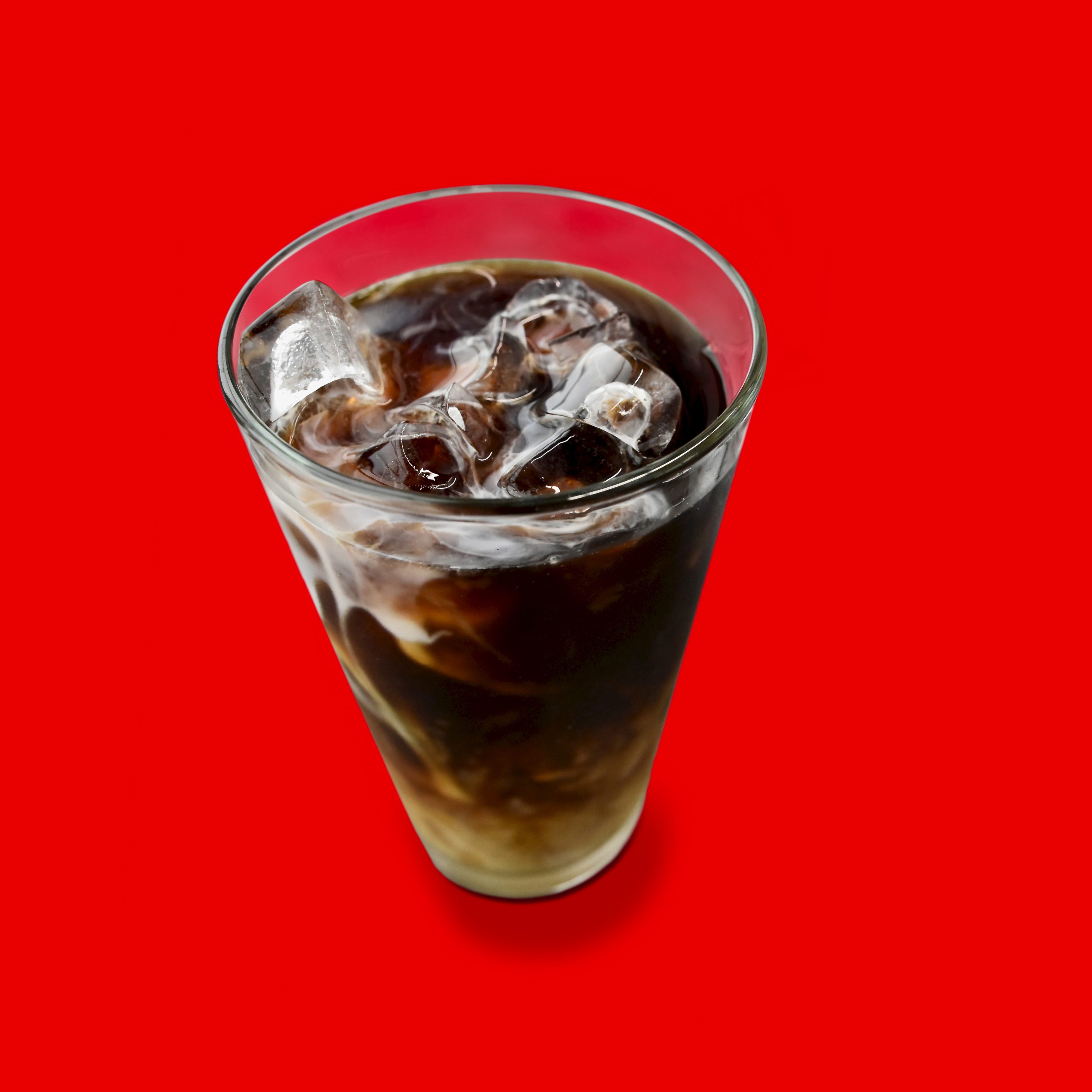 Iced Coffee in glass with ice on red background